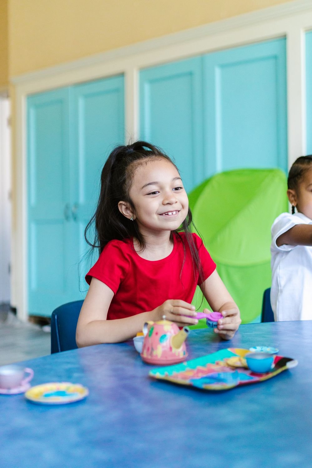 A young child smiling while building with colourful blocks at a Damara International classroom table
